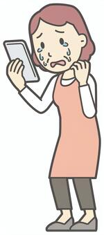  スマホを見て泣いているおばさん スマホ,女性,人,主婦,中年,シニア,エプロン,ママ,お母さん,おかんのイラスト素材