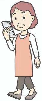  スマホを見ながら歩いている中年の女性 スマホ,おばさん,人,女性,中年,おばちゃん,シニア,ママ,主婦,ヘルパーのイラスト素材